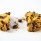 A homemade chocolate cookie with a bite and crumbs on a white background