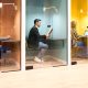 Train coworkers each sitting at the desk in their office cabin with a glass door, working