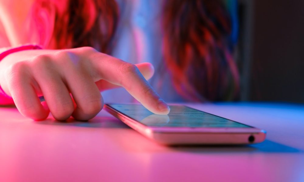 person touching a smartphone laying on a table.