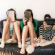 Three kids holding tablets sit on a couch