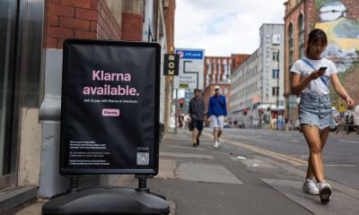 Members of the public pass by a floor advertisement for tech firm Klarna.